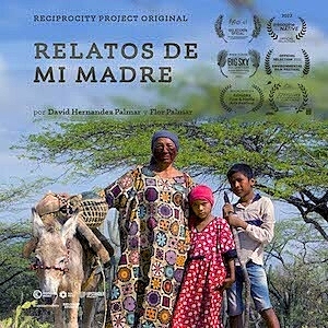 A women in a long dress and face paint stands next to two children and a donkey