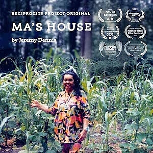 A women in colorful cloths stands with a crop of plants outside