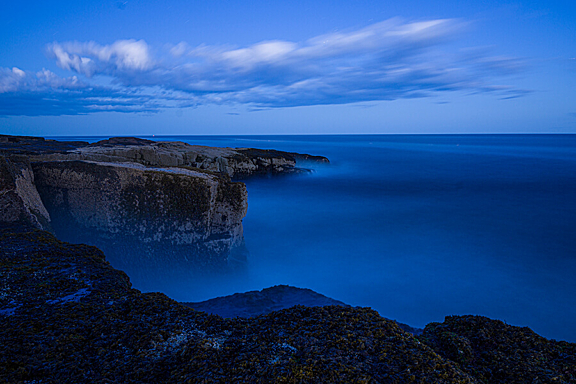 Deep blue sky and fog over a cliff