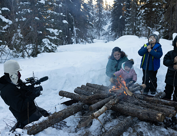 Crew filming a family gathered around a fire