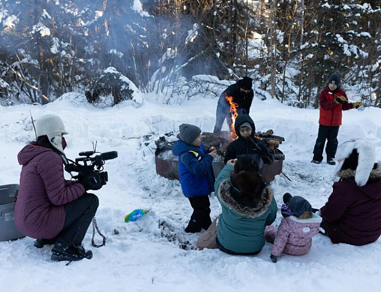 Crew filming a family gathered around a fire