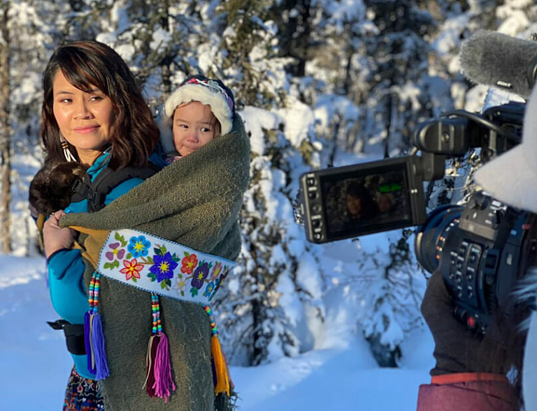 Woman with child in tow on her back being filmed