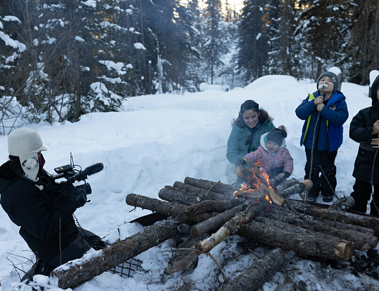 Crew filming a family gathered around a fire